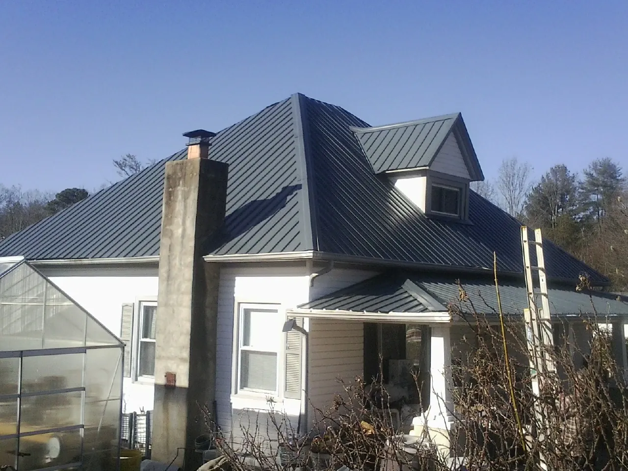 Dark blue standing seam metal roof on a white farmhouse with dormer — Slate & Tile Roof Repair by Roofing Brothers in Houtzdale