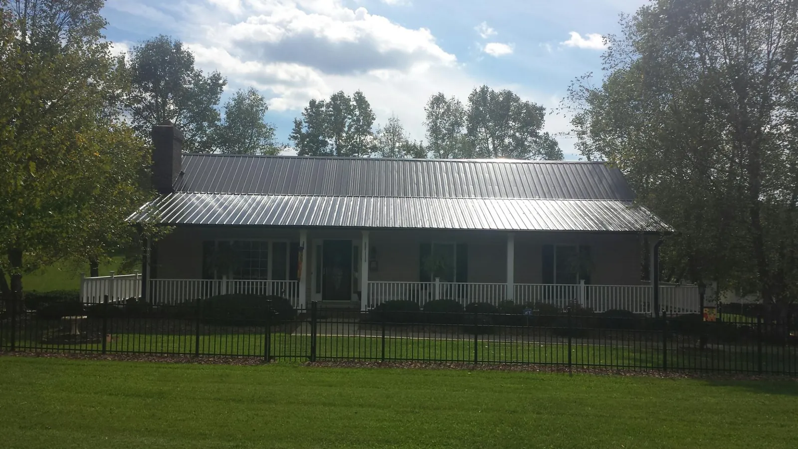 Gray metal roof on a brick ranch with a full width front porch — Gutter Guard Installation work by our crew in Houtzdale