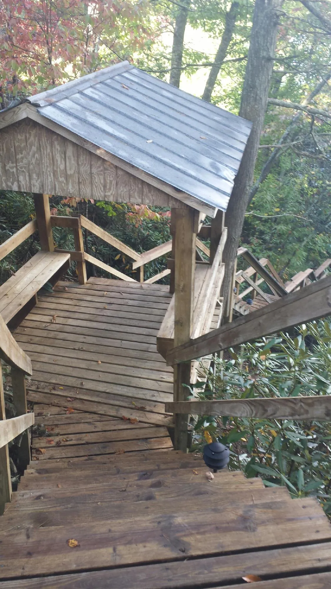 Metal roofed shelter over wooden steps on a wooded walkway — Skylight Repair & Installation work by our crew in Houtzdale