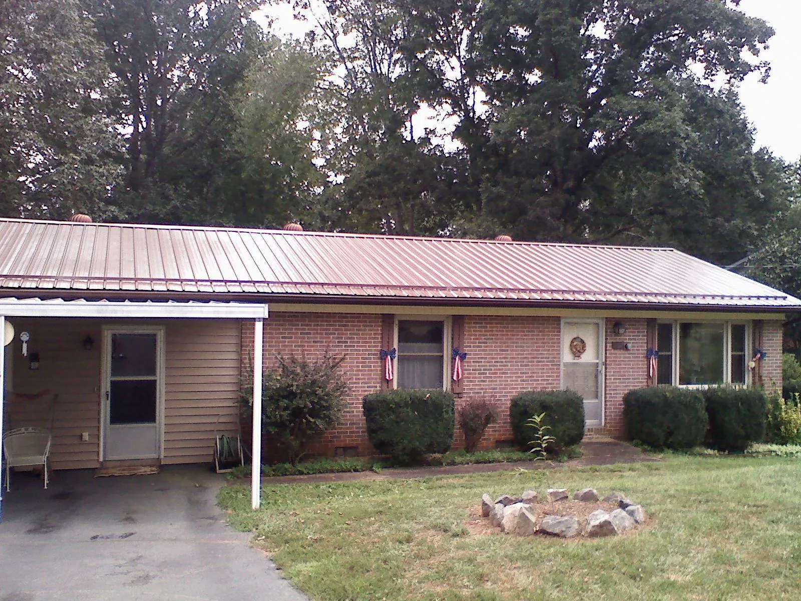 Bronze metal roof and carport on a brick ranch home — Roof Repair work by our crew in Houtzdale