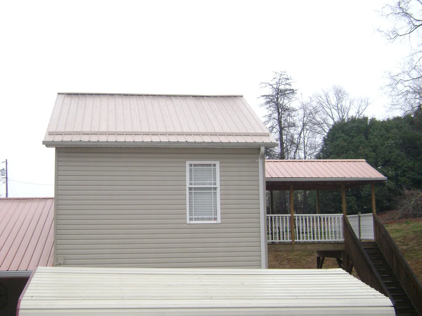 Tan metal roofs on a two story addition and attached porch, from a Roof Replacement job in Houtzdale