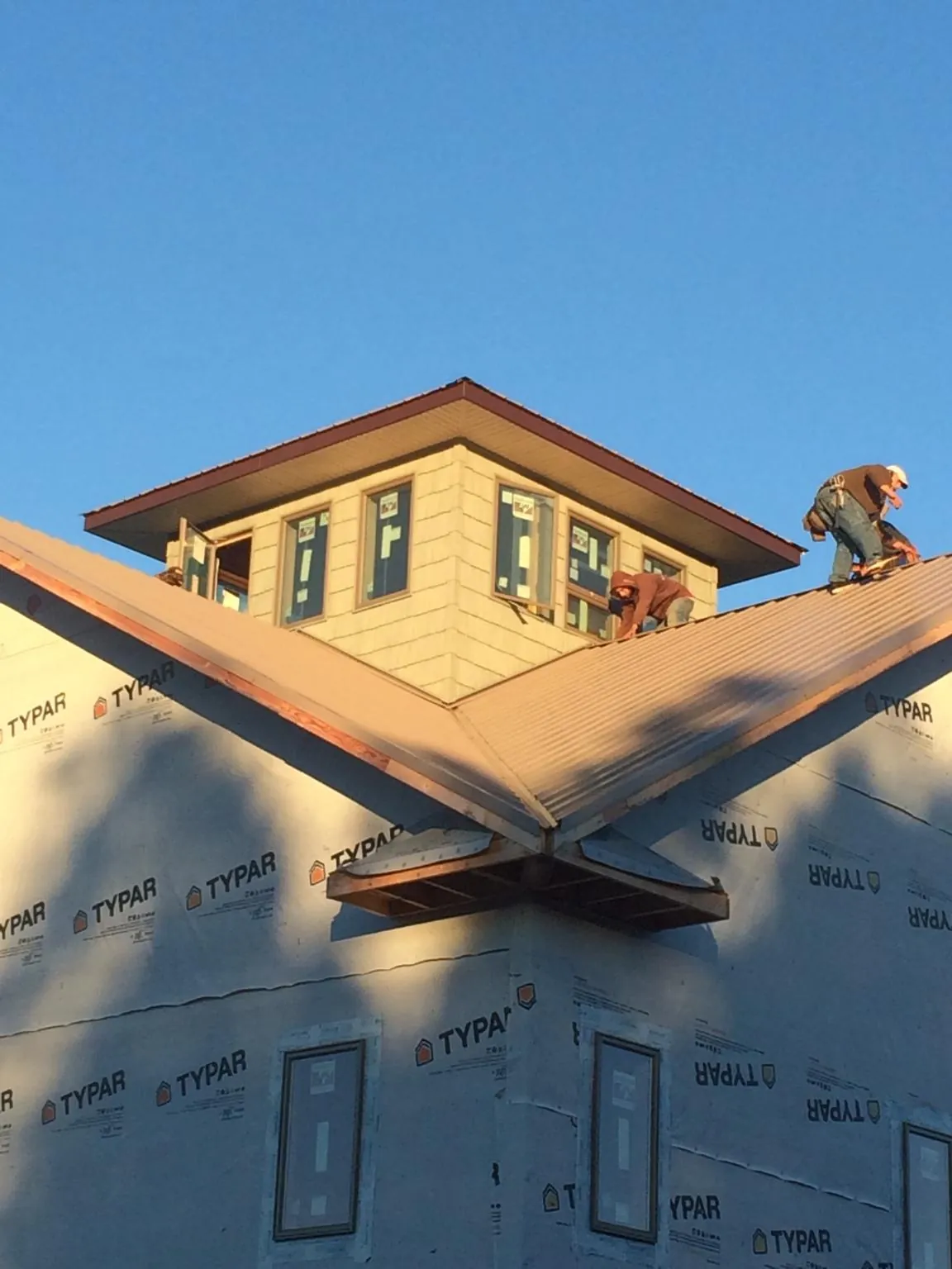 Roofers working around a rooftop cupola on a new metal roof at sunset — Roof Waterproofing in Houtzdale by Roofing Brothers